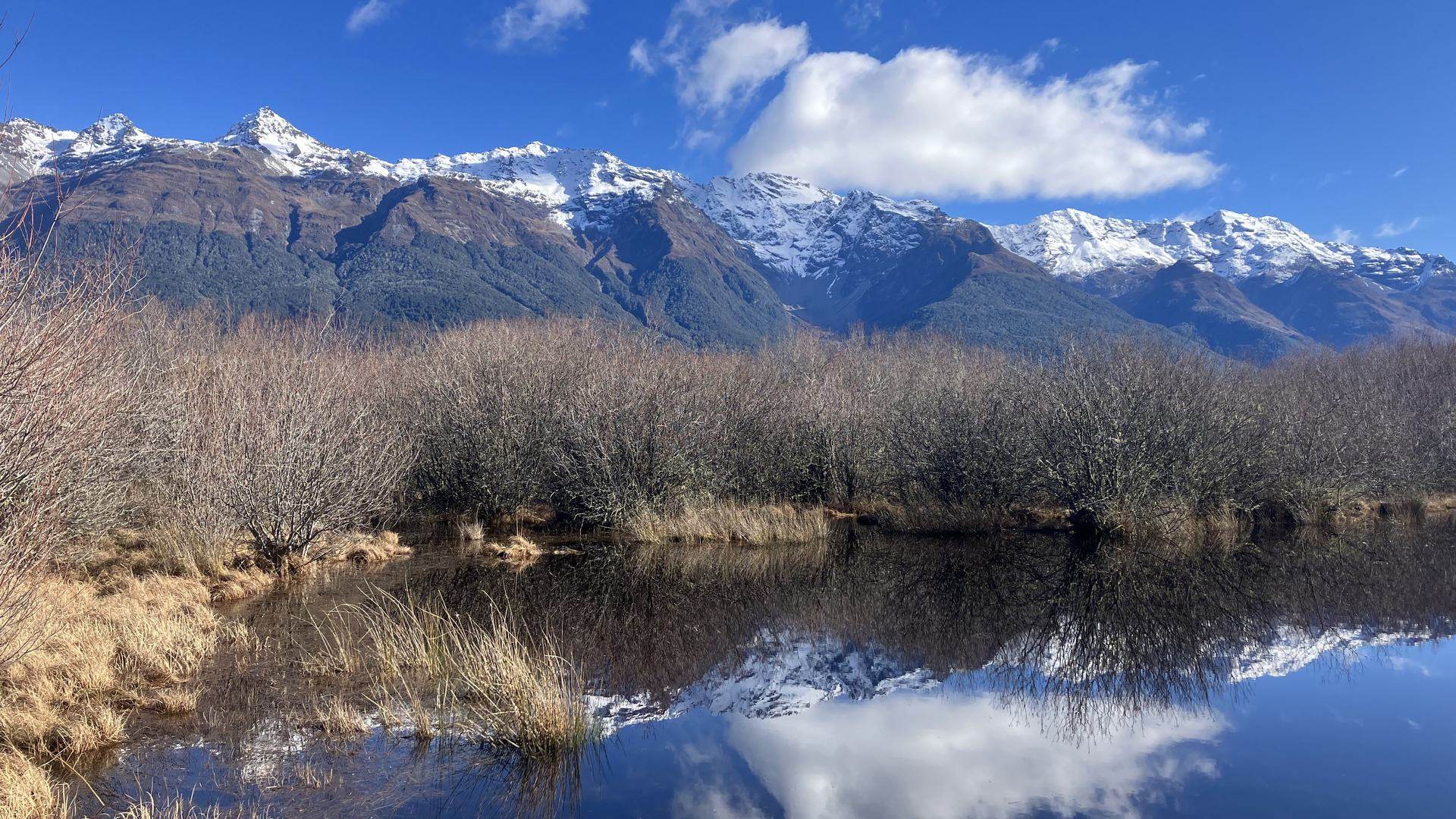 Snow-capped mountains mirrored in a still tarn